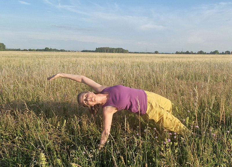 Katharina in Yoga-Pose auf einer sommerlichen Wiese